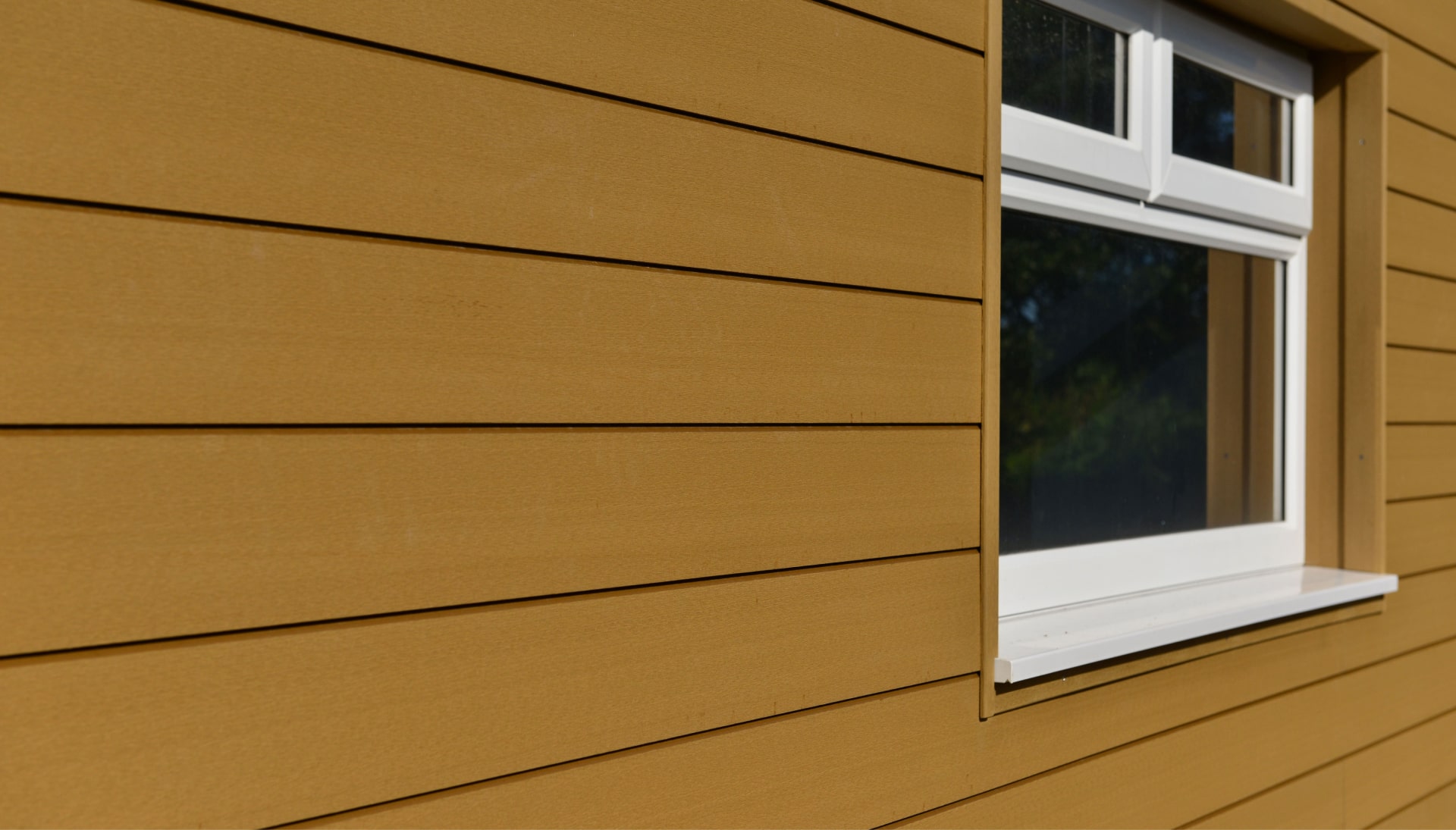 Advanced composite siding in a mustard brown color being installed in an older home.